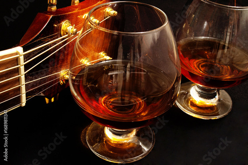 Canvas Print Glass of cognac and on the classic guitar