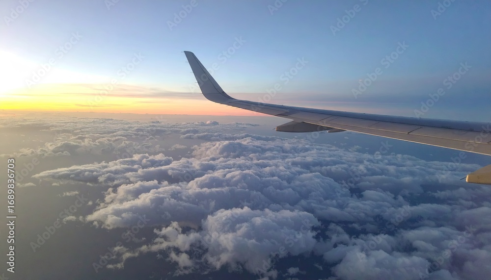 Obraz premium Airplane Wing Above Clouds at Sunrise