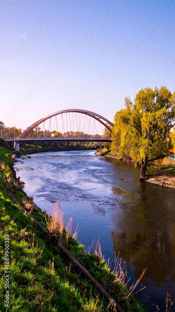 Naklejka premium Scenic river view with a bridge and lush greenery