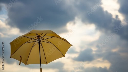 Yellow umbrella standing alone against a cloudy sky, evoking a sense of solitude and calmness