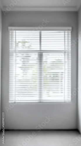 Soft-focus shot of a window with white venetian blinds in a gray room. Natural light streams in, creating a tranquil, minimalist atmosphere