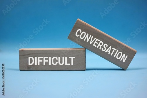 Wooden Blocks Displaying Words 'Difficult' and 'Conversation' Isolated on blue. symbolizing challenging discussions and complex communication themes.