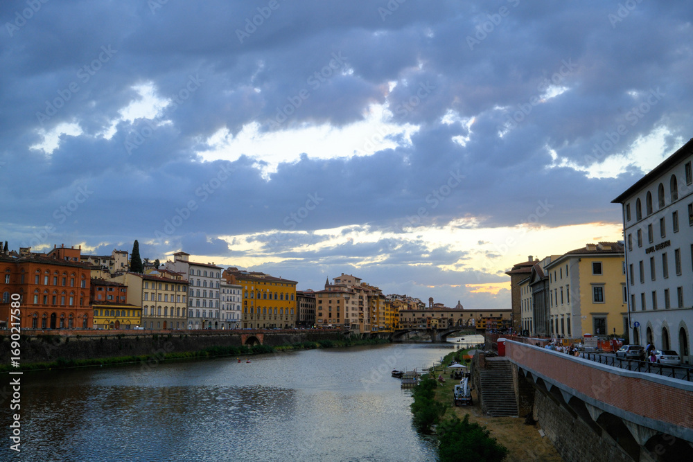 Fototapeta premium Florence, Italy – view of the Arno River with historic buildings along the riverside and Renaissance architecture reflecting in the water.