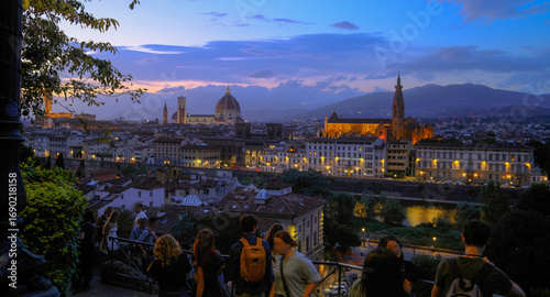 Florence, Italy at night with illuminated cathedral, Arno River reflections, and historic city skyline.