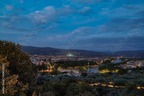 Florence, Italy at night with illuminated cathedral, Arno River reflections, and historic city skyline.