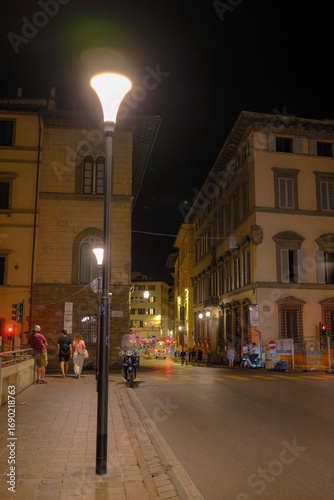 Florence, Italy at night with illuminated cathedral, Arno River reflections, and historic city skyline.