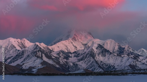Snow capped mountains at sunset with a pink glow