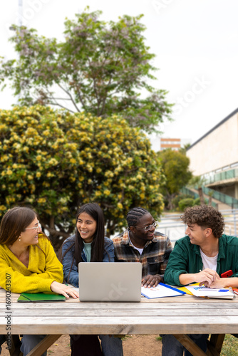 University students collaborating on project outdoors with laptop