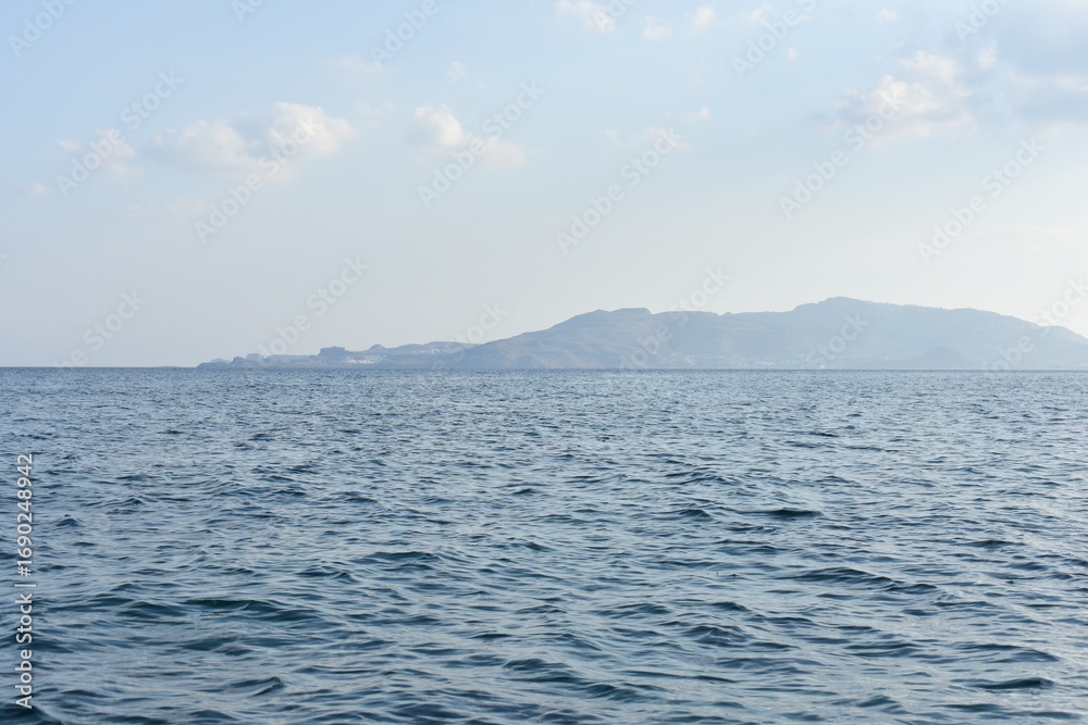 Obraz premium Panorama of Rhodes Island from the sea. Beautiful sea landscape. Holidays and travel to Greece. Motorboating during vacation. Boat rental. Summer vacation at sea. Tourist boat trip. 
