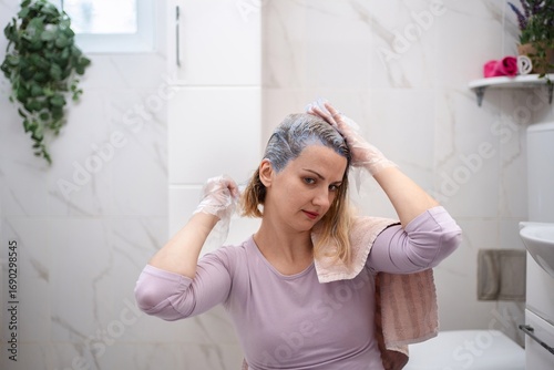 Bilde på lerret Woman dyeing her hair at home in the bathroom
