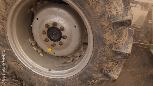 Agricultural tractor ploughing in a field in natural light turning the soil as dust rises. The powerful motion of the blades reveals fresh earth, essential for agriculture and farming. India