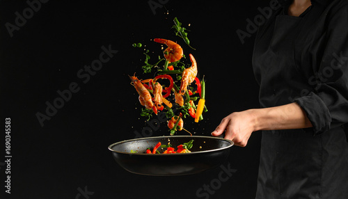 Chef tossing shrimp with vegetables in a frying pan against dark backdrop