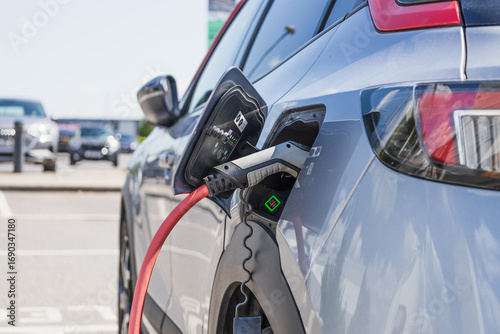 Electric Car Charging at Public Parking Lot. Close Up Plugged In EV