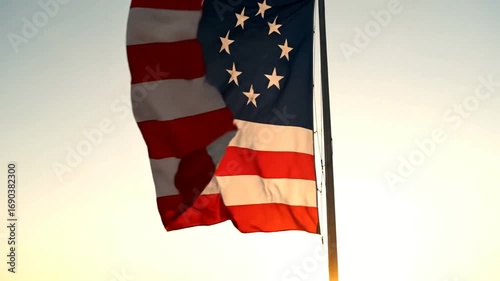 The Betsy Ross American flag with thirteen stars in a circle waving against a bright sky.