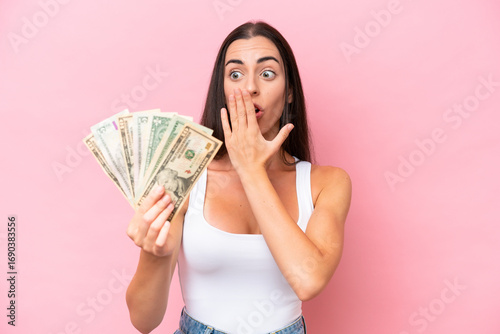 Fotografie Young caucasian woman taking a lot of money isolated on pink background with sur