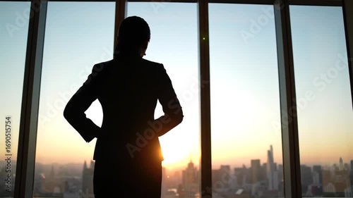 Silhouette of a businesswoman gazing at a city skyline during sunset, reflecting on her day