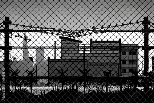 chain link fence, barbed wire, industrial, grungy, weathered, monochrome, high contrast, abstract texture.