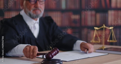 Judge with gavel delivering verdict, court ruling during hearing of criminal case in courtroom. Elderly magistrate sitting at desk and holding wooden hammer to approve and announce decision