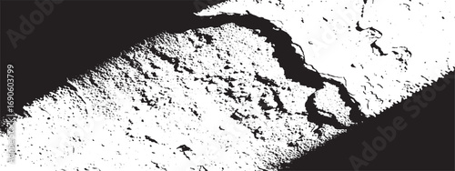 Textured surface with harsh shadow and light contrast creating dramatic black and white graphic pattern