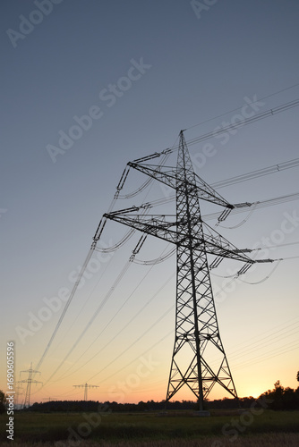 High-voltage electricity pylon photographed from below at blue hour shortly after sunset, silhouetted against the evening sky in Germany.