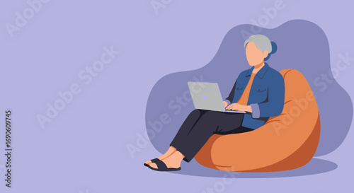Senior woman comfortably working on a laptop while sitting on a bean bag chair. Illustrates modern remote work, online learning, or digital leisure time.