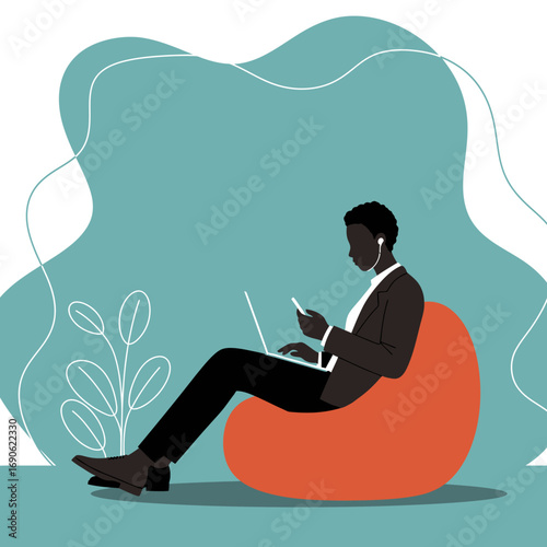 Focused Black man working remotely on laptop and phone from a comfortable bean bag, showcasing modern productivity and flexible work-life balance.