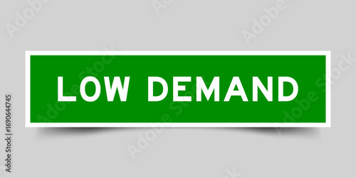 Green color square shape sticker label with word low demand on gray background