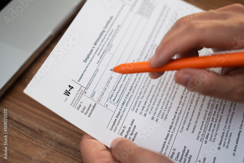 Принти на полотні Male corporate intern sits with laptop at table filling out W-4 form to provide