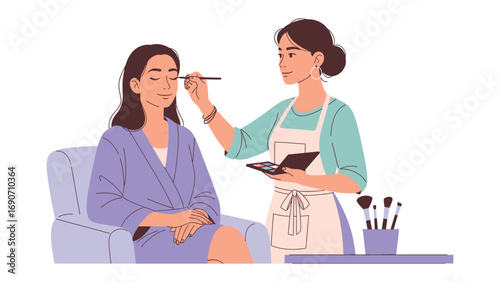 Professional makeup artist applying eyeshadow to a young woman sitting in a chair wearing a robe in a beauty salon setting
