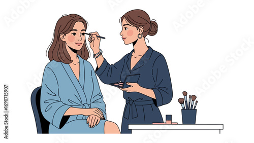 Professional makeup artist applying eyeshadow to a young woman client wearing a blue robe in a clean studio setting
