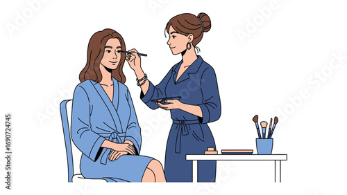 Professional makeup artist applying cosmetics to a client sitting in a chair wearing a blue robe in a studio setting