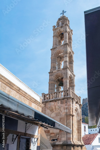 Memory and marker , bell tower standing tall above whitewashed alleys, this stone relic echoes centuries of Lindos’ layered identity beneath the wide Aegean sky.