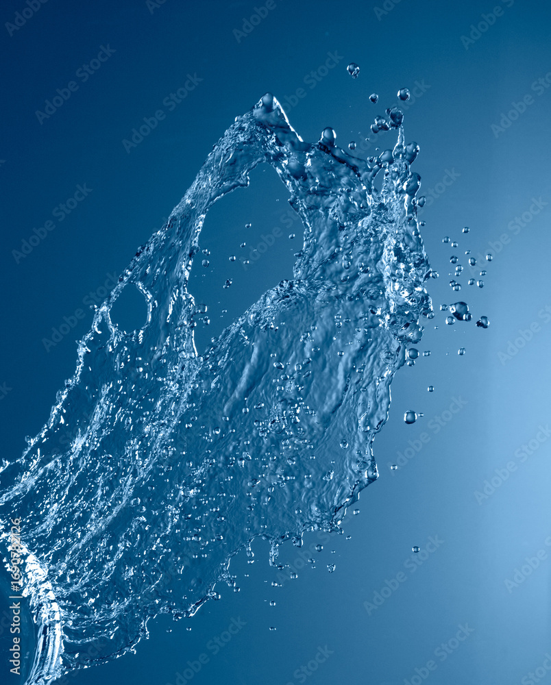 Obraz premium Splash of water frozen mid-air against blue background, showing fluid motion and surface tension.