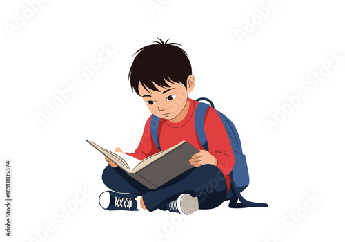 Young boy sitting cross legged reading a book wearing backpack