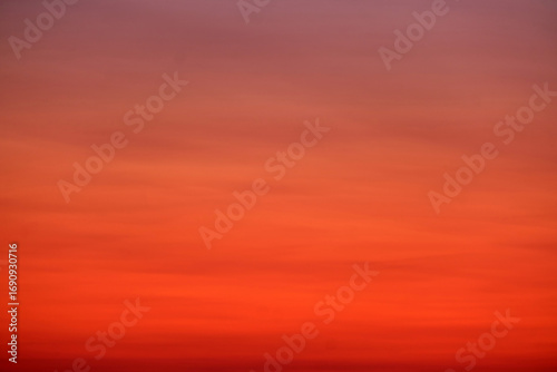A smooth gradient sky with warm red, orange, and purple tones at sunset, ideal for backgrounds, textures, or design projects.