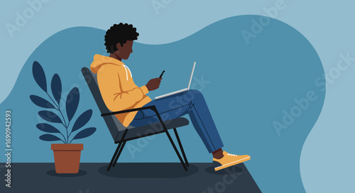 African American man uses a laptop and phone while relaxing in a chair, embodying remote work, digital learning, and a connected lifestyle.