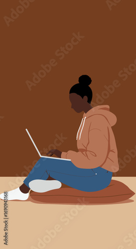 Young Black woman comfortably working or studying from home, using her laptop while sitting on a cushion. Ideal for remote work, education, or modern lifestyle content.