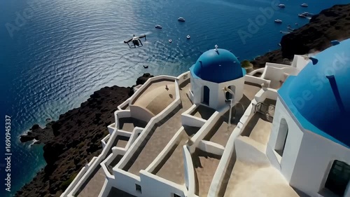 Breathtaking aerial view of iconic white buildings with blue domes overlooking the sparkling Aegean Sea.