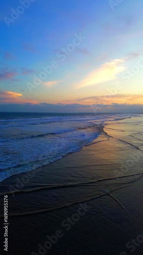 Relaxing Sunset Waves on Sandy Beach – Vertical Nature Video. Vertical video of calm ocean waves at sandy beach sunset, ideal for travel, nature, relaxation.