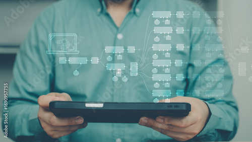 Businessman using tablet with holographic workflow automation interface. Concept of AI automation, N8N style flow, digital transformation, and automatic process management.