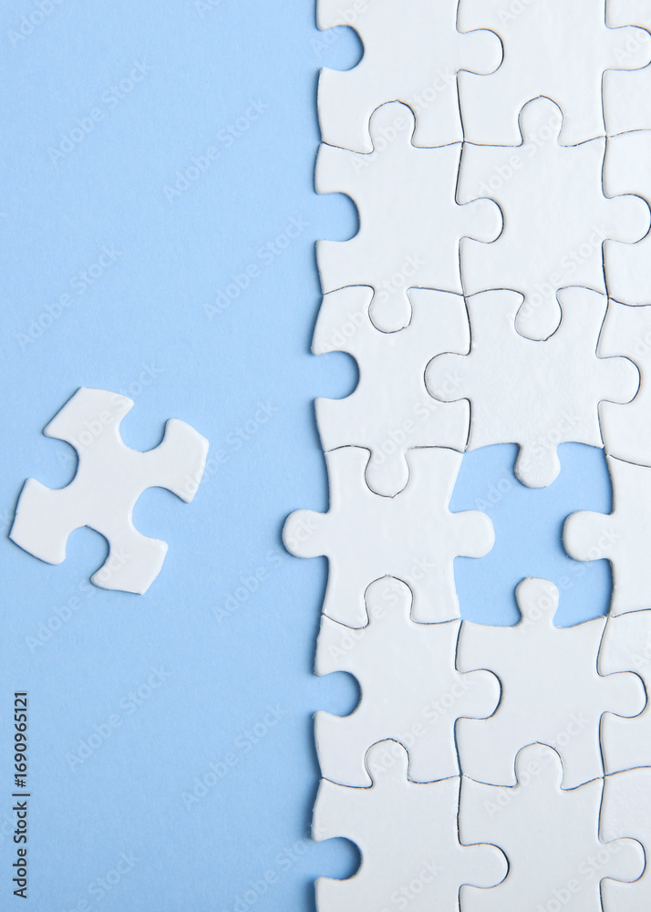 Fototapeta premium White puzzle on a colored background top view.. Vertical photo format
