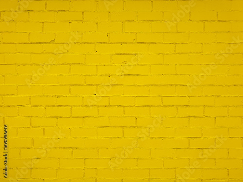 Textured yellow brick wall with uneven surface. Rough and grunge texture. Brick painted with yellow paint. Uneven, sloppy brickwork