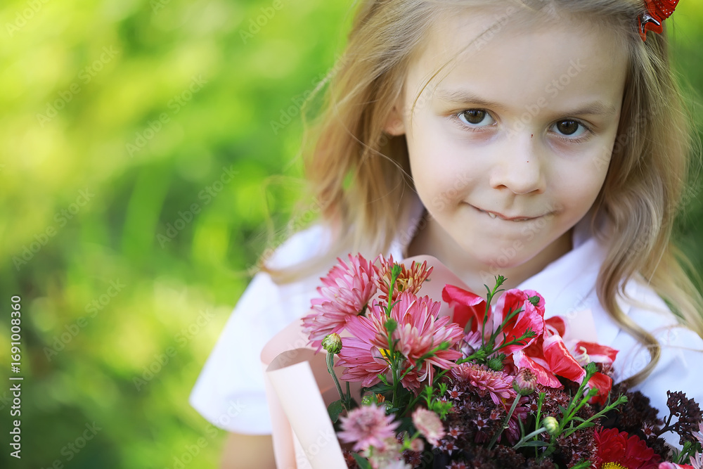 Fototapeta premium Smiling Girl Holding a Bouquet of Colorful Flowers in a Garden on a Bright Summer Day