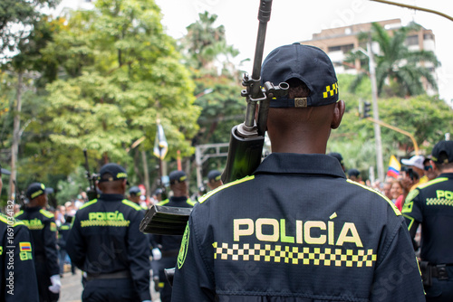 Police officer from behind with rifle, Armed policeman rear view, Law enforcement carrying firearm on back. High quality photo