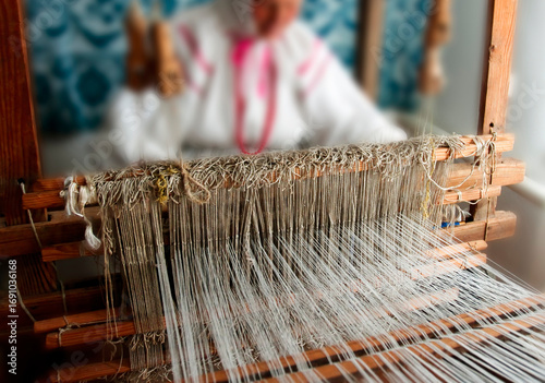 Crafting intricate textiles at a traditional loom in a cozy workshop during the daylight hours