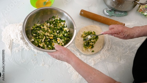 Baker making green onion pie on floured table