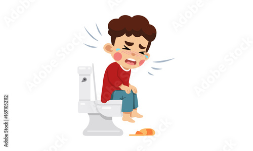 A young boy sitting on a toilet, crying and looking distressed, with a small pill on the floor next to him.