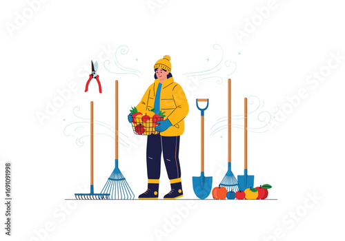 Gardener in a yellow jacket holding a basket of fall harvest fruits vegetables and gardening tools