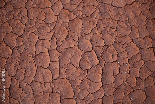 Dry, red-brown, cracked and dusty ground surface. Soil erosion. Cracked red clay top view