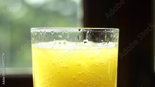Refreshing Orange Juice Filled in Transparent Glass with Bubbles by the Window
